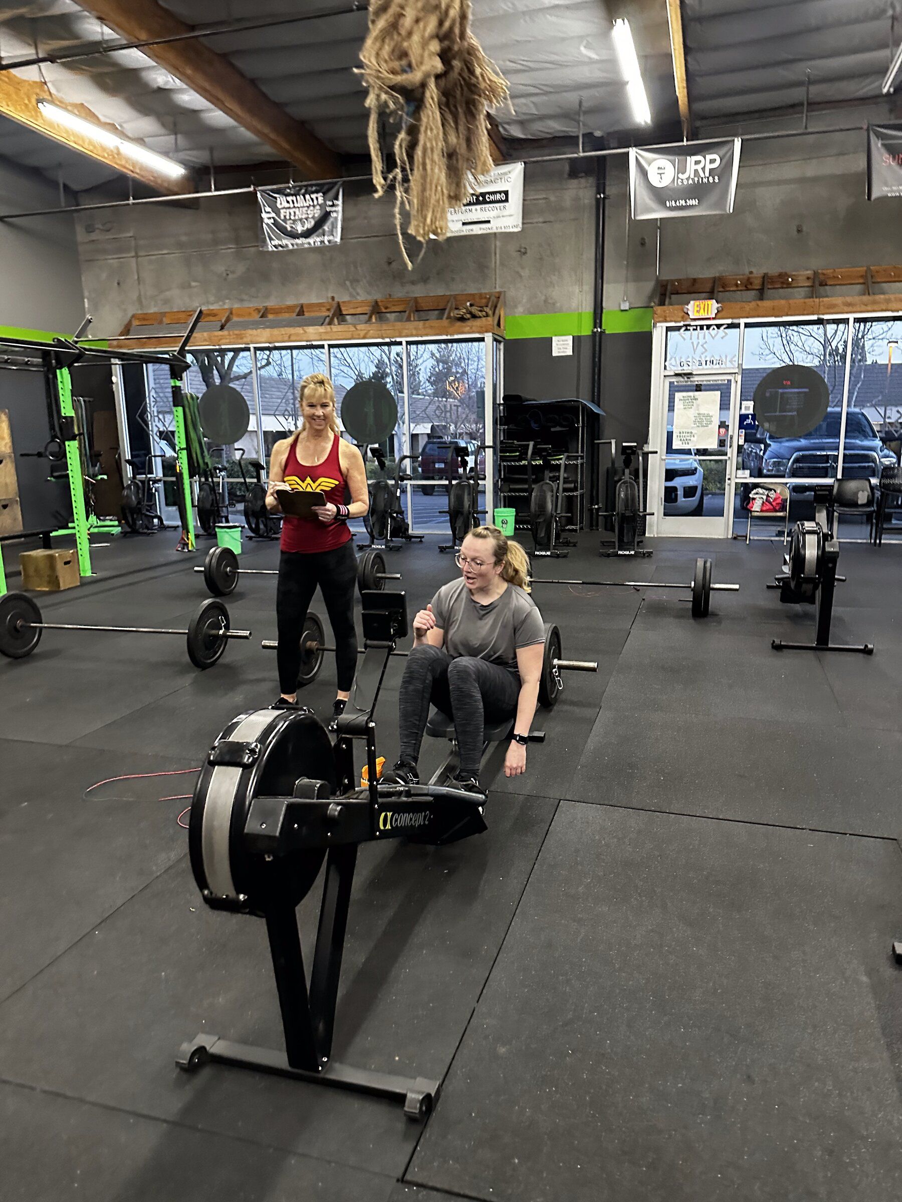 A coach times a member rowing on the gym floor at EDHFIT